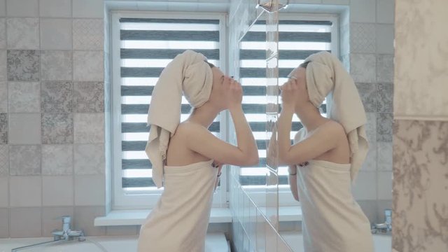 Young, pretty woman with towel on head and body paints her eyes in bathroom. Beauty and makeup concept