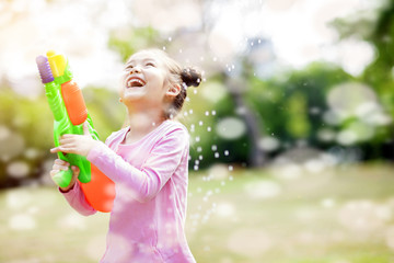 happy little girls playing water guns in the park.
