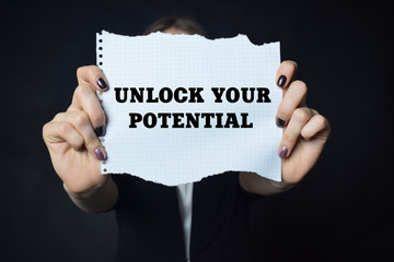 In the hands of a businessman a scrap of paper with the inscription:UNLOCK YOUR POTENTIAL