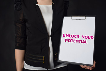 In the hands of a businessman a notebook with the inscription:UNLOCK YOUR POTENTIAL