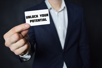 Businessman shows business card with the inscription:UNLOCK YOUR POTENTIAL