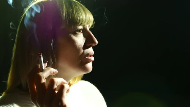  4K.Adult woman  smoke cigarette . Close up, black background 