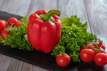 Salad, red pepper and tomatoes on a black board.