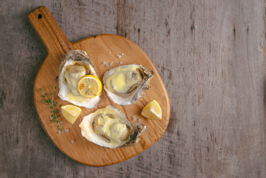 Opened oysters and lemon on wooden board.