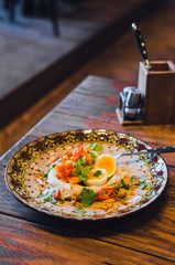 Hummus, baba ghanoush dip with poached eggs, parsley, and chilli. Traditional Middle Eastern appetizer. Colorful ornated plate