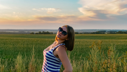 Pretty young girl in a field on sunset