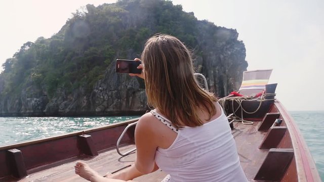 Young woman traveling on wooden boat takes pictures on the camera phone during a travel, slow motion. 1920x1080