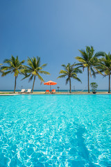 swimming pool and the blue sea with palmcoconut trees