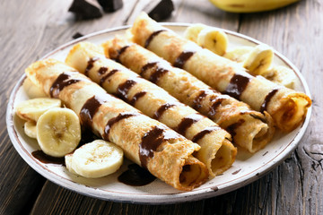 Crepes roll with banana, kiwi slices and chocolate sauce