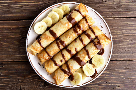 Crepes roll with banana, kiwi slices and chocolate sauce