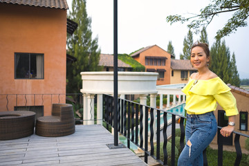 asian girl wearing yellow shirt and jeans posing in emotional smile happy