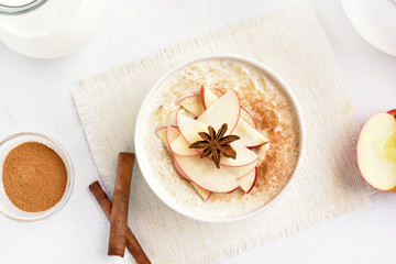 Fototapeta na wymiar Oatmeal porridge with red apple slices and cinnamon