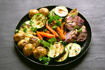 Grilled vegetables on dark plate.