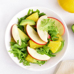 Fruit vegetable salad with red apples, avocado, orange slices