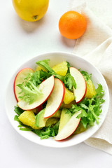 Fruit vegetable salad with red apples, avocado, orange slices