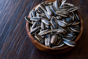 Black Unsalted Sunflower Seeds in Wooden Bowl.