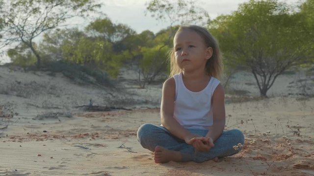 Child girl sits at desert and pondering somethink with thousand-yard stare