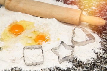 flour and eggs with molds on the table and roller