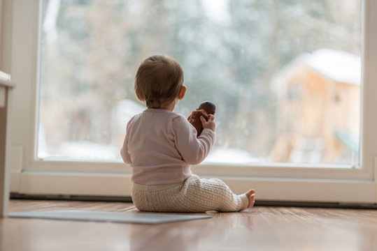 Little baby girl watching the snow outdoors