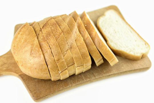 Fresh baked bread on wooden cutting board. Bun slice on isolated white background.