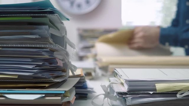 Employee working in the office and piles of paperwork