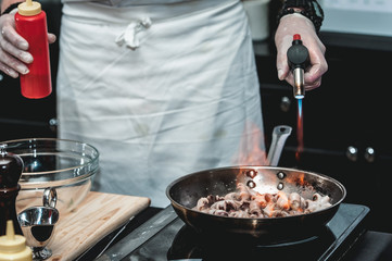 The chef cooks the small octopus on a metal frying pan