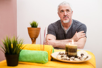 Adult male masseur sitting in the workplace in a massage parlor