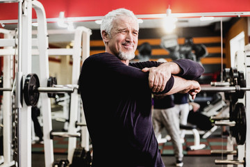 Adult man with gray hair warms up before playing sports in the gym