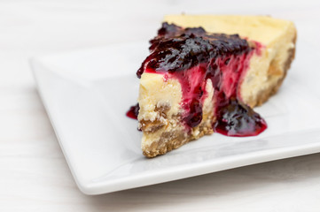 Piece of heesecake with jam on saucer.