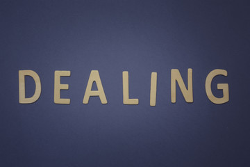 Dealing written with wooden letters on a blue background