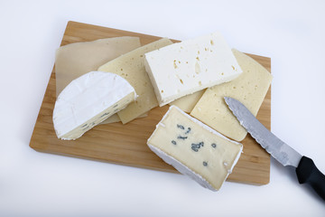 Verschiedene Käsesorten auf einer Holzplatte über weißem Hintergrund