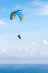 Fototapeta na wymiar Flying tandem paraglider over the sea, vertical shot