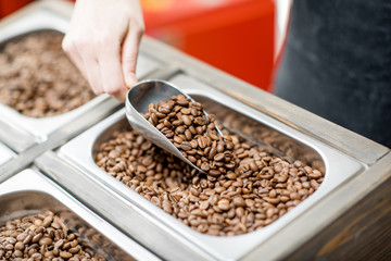 Getting coffee beans from the metal tray with scoop in the store. Close-up view