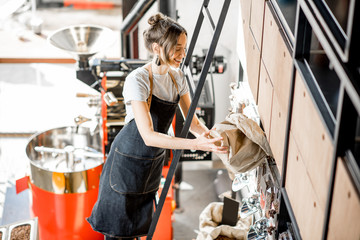 Woman in sales uniform filling tray with coffee standing on the ladder in the coffee shop