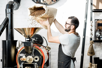 Man pouring coffee beans into the roaster machine indoors