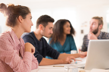 At office. Meeting around a table, a young multiethnic team shar
