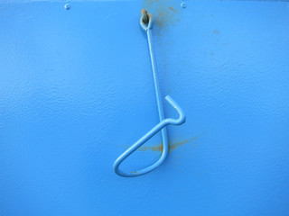 light blue painted twisted metal hook on a metal door