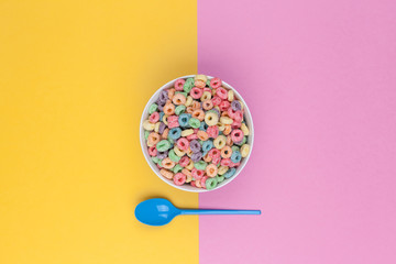 Fototapeta na wymiar Bowl of colorful cereals and spoon top view