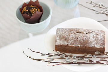 Кекс на белой тарелке с ветками вербы. Кекс в голубой керамической миске