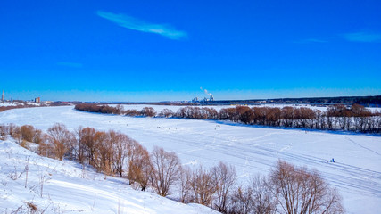Fototapeta na wymiar Frozen river winter covered with snow. Beautiful lake landscape in ice. Clear blue sky with clouds.