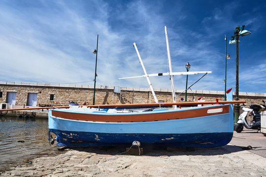 A wooden sailboat on the quay of the port of Saint Tropez in France.