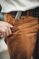 a man's hand with an engagement ring in a pocket of brown trousers