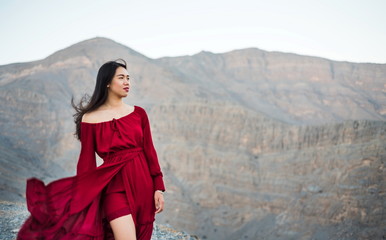 Fashionable girl in red dress on a desert mountain top