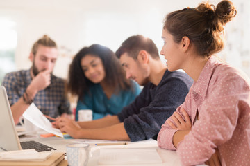 At office. Meeting around a table, a young multiethnic team shar