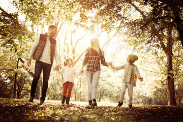 Happy family walking trough park and holding hands.