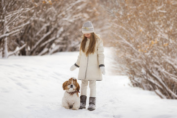 beautiful little girl with her dog on the snow in winter