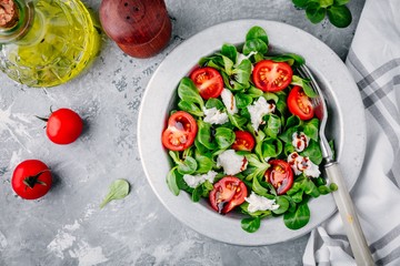 fresh salad bowl with green leaves, mozzarella, tomatoes and balsamic sauce