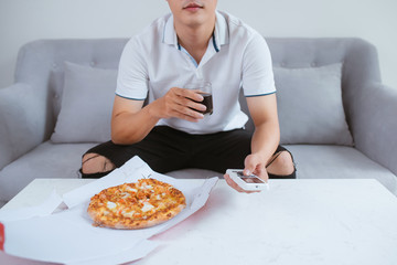 Man watch TV and eating pizza with soft drink. Close up. Sitting on sofa