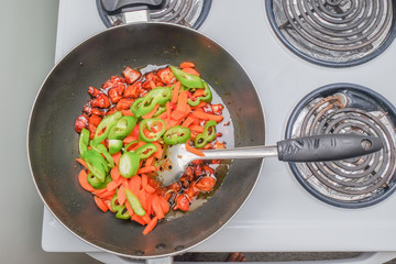 Chicken cooked oyster sauce with green chillies, red chillies and carrots in a pan