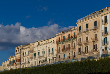 Fototapeta na wymiar Row of buildings at the tree-lined seafront promenage on the Isle of Ortygia